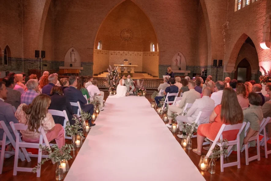 Wedding ceremony in brick church with white aisle runner