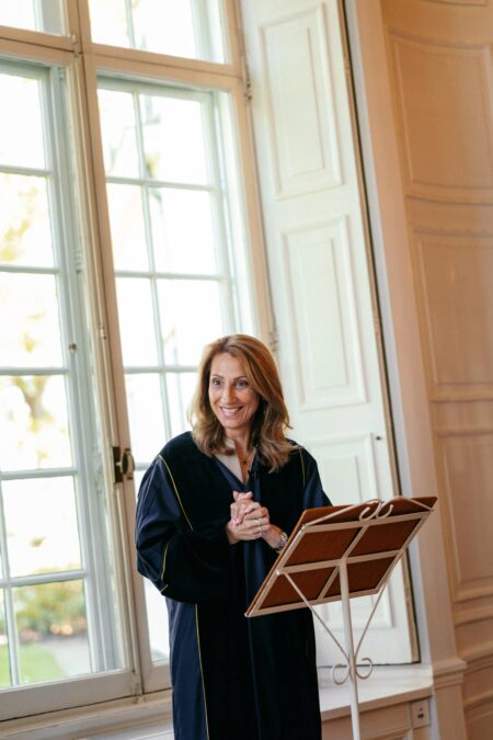 Woman in navy jacket reading from music stand by window