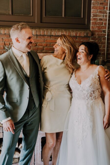 Three people laugh together at indoor brick wall venue
